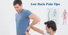 Managing Low Back Pain: Tips for Home Exercises. Picture of a young caucasian male with a young caucasian physical therapist, checking his lower back.